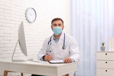Photo of Portrait of pediatrician with protective mask at table in clinic