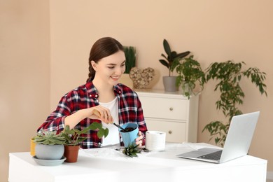Photo of Woman taking care of plant following online gardening course at home. Time for hobby