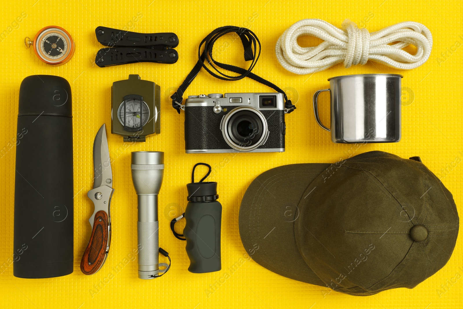 Photo of Flat lay composition with different camping equipment on yellow sleeping mat. Traveler set