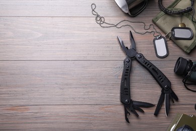 Flat lay composition with compact portable multitool and accessories on wooden table. Space for text