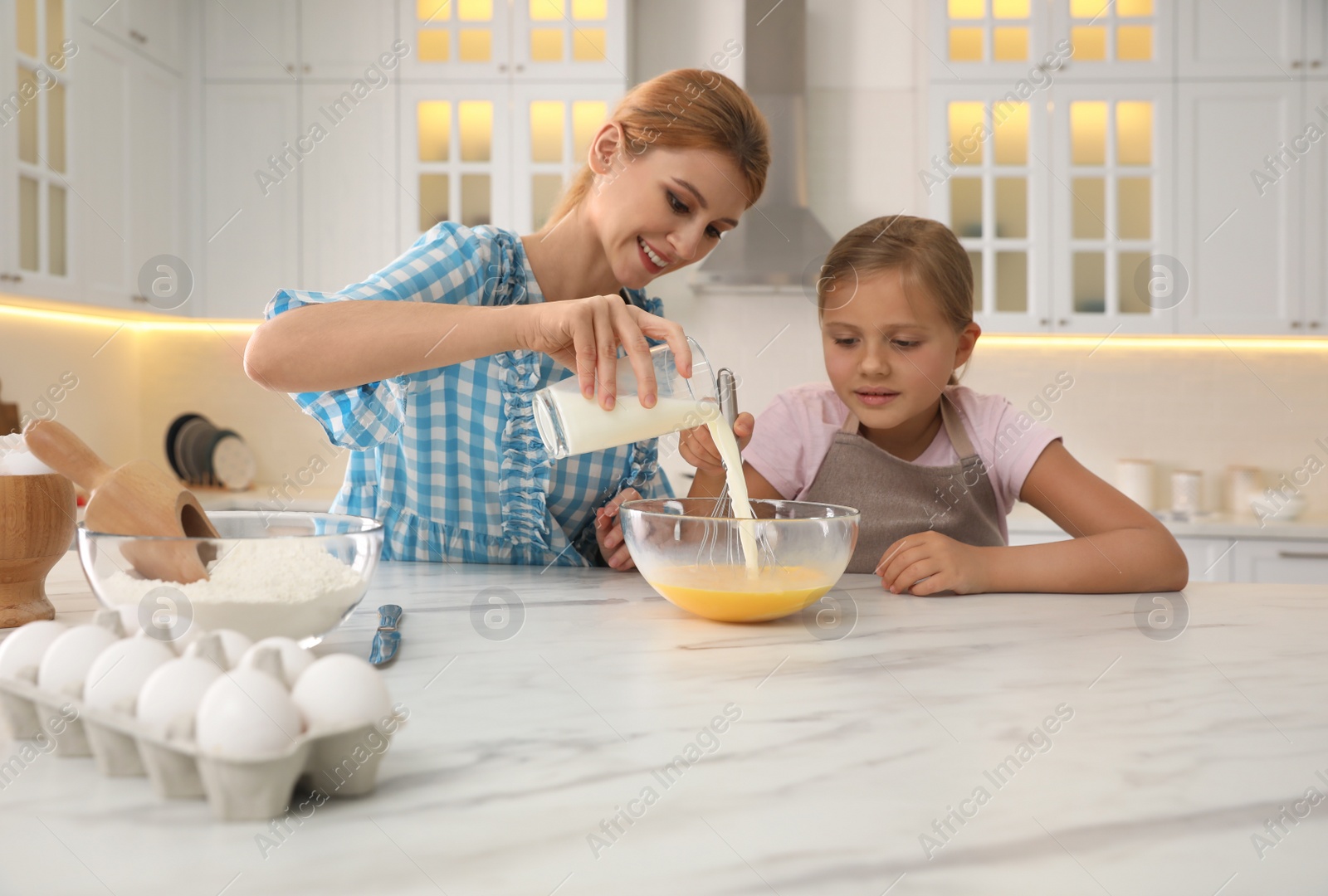 Photo of Mother and daughter making dough together in kitchen