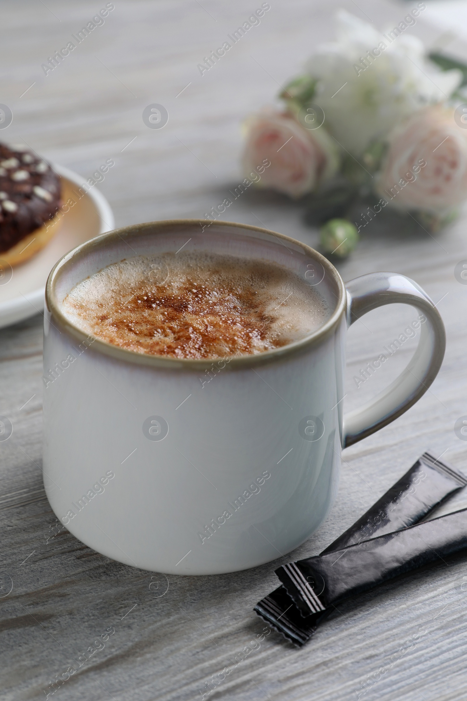 Photo of Delicious coffee in cup and sugar packets on white wooden table