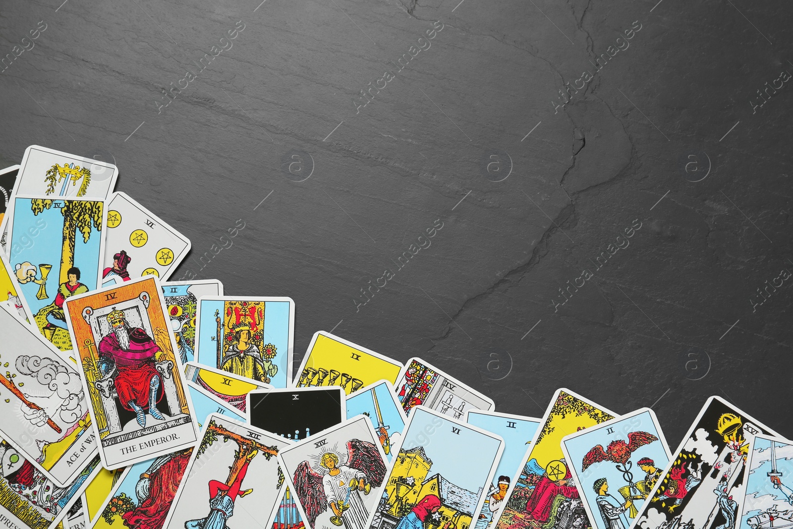 Photo of Tarot cards on black table, top view. Space for text