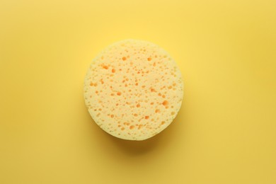 Photo of New sponge on yellow background, top view
