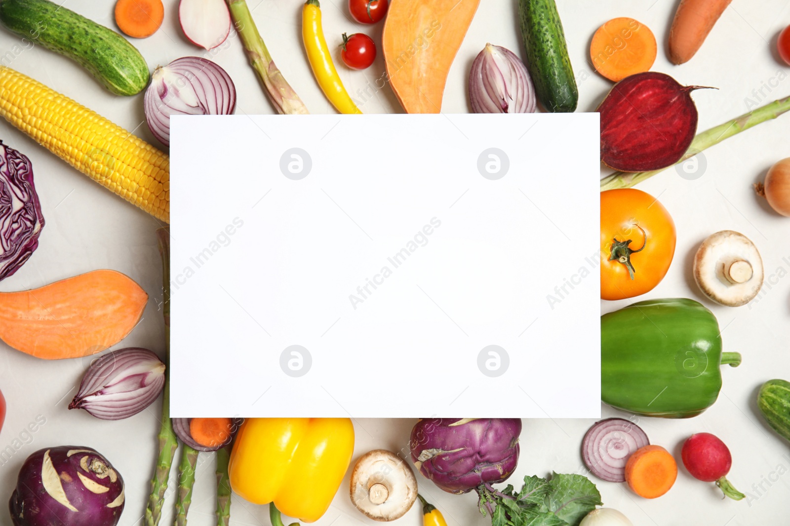 Photo of Flat lay composition with fresh vegetables and blank card for text on light background