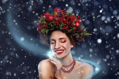 Beautiful young woman wearing Christmas wreath on dark background
