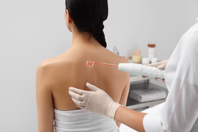 Photo of Woman undergoing physiotherapy procedure with darsonval in salon, back view