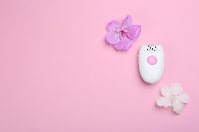 Photo of Modern epilator and flowers on pink background, flat lay. Space for text