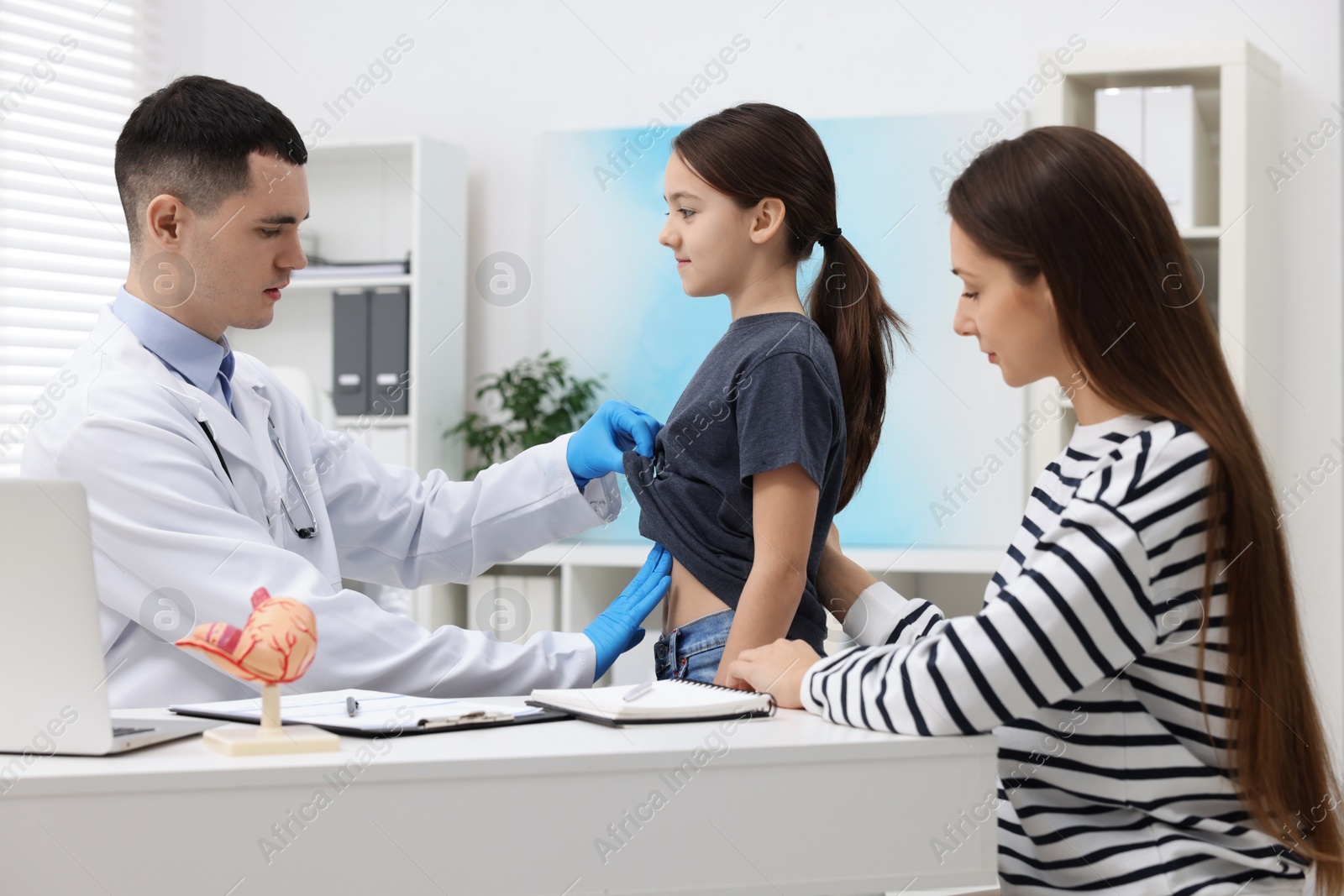 Photo of Gastroenterologist examining girl with stomach ache in clinic