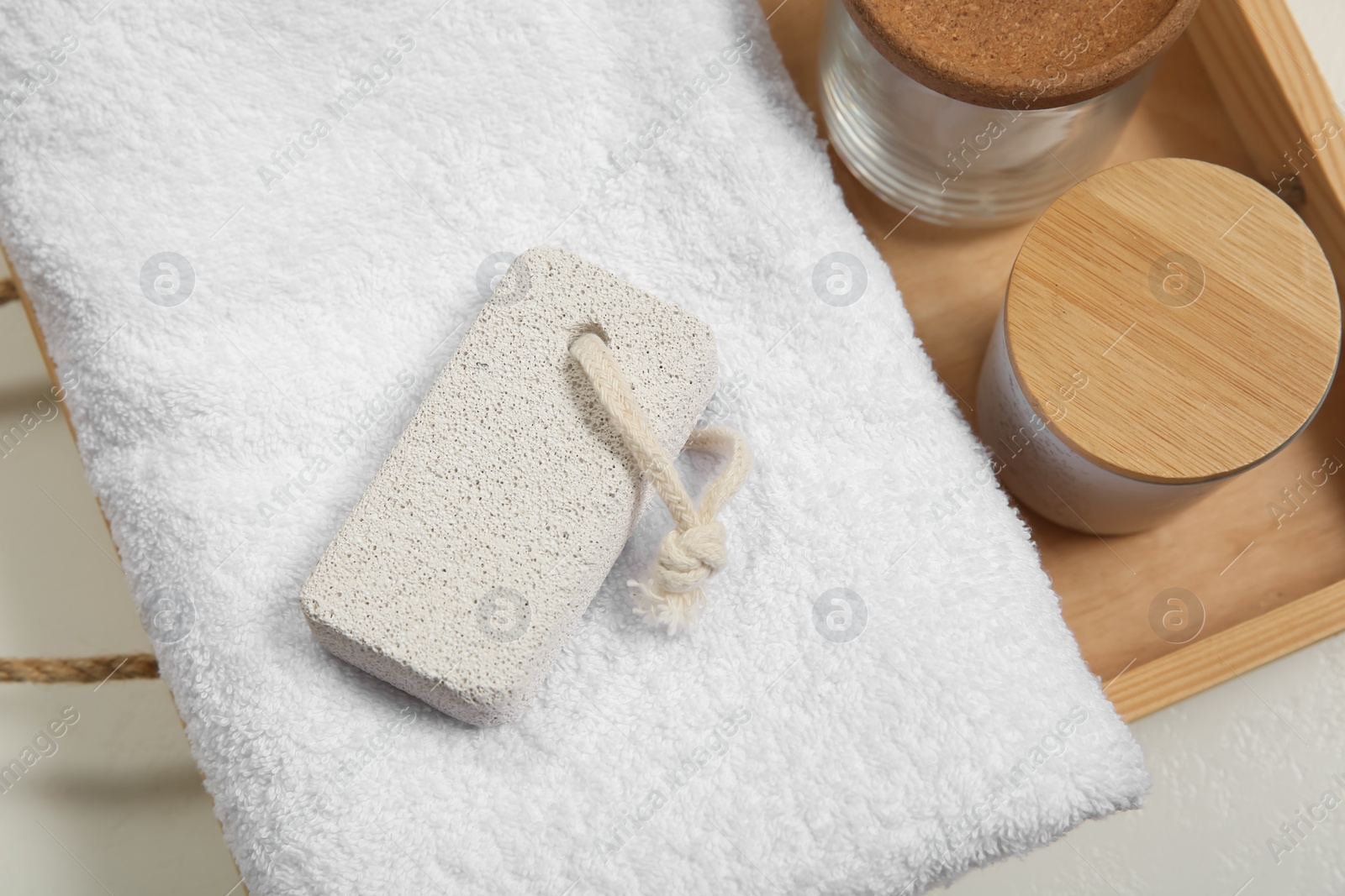 Photo of Pumice stone, towel and jars on white table, above view