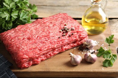 Photo of Raw ground meat, spices, parsley and oil on wooden table