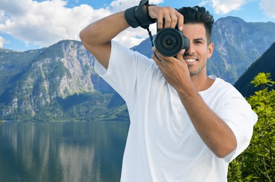 Image of Photographer holding professional camera and beautiful view of mountains on background
