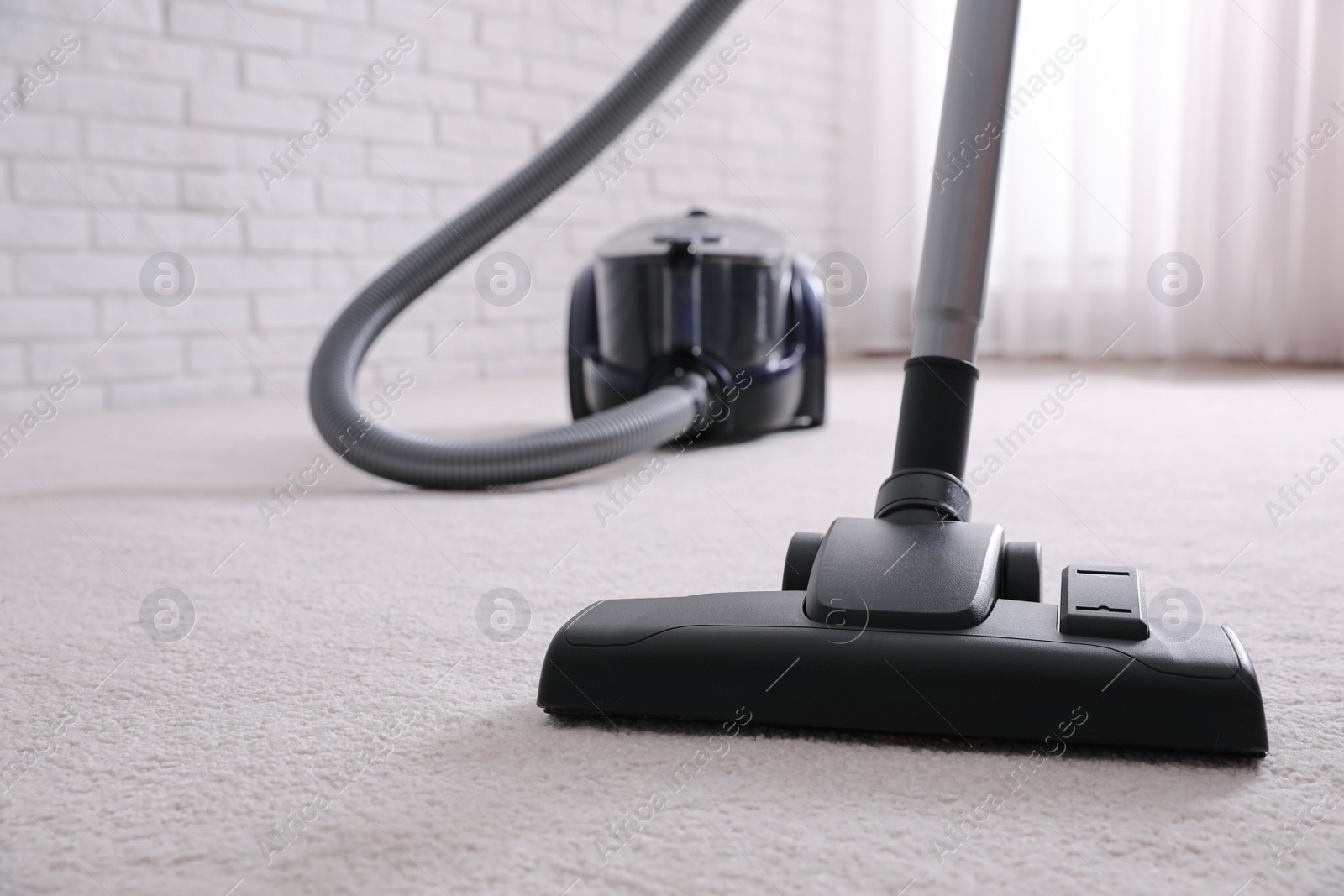 Photo of Modern vacuum cleaner on carpet indoors, closeup. Space for text