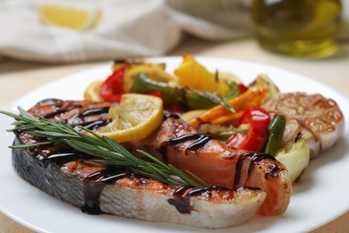 Tasty salmon steak with sauce, lemon and vegetables on light table, closeup