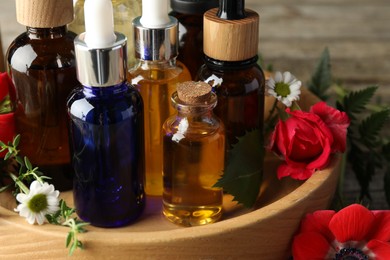 Photo of Aromatherapy. Different essential oils and flowers on table, closeup