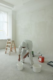 Photo of Decorator in uniform with buckets of paint indoors