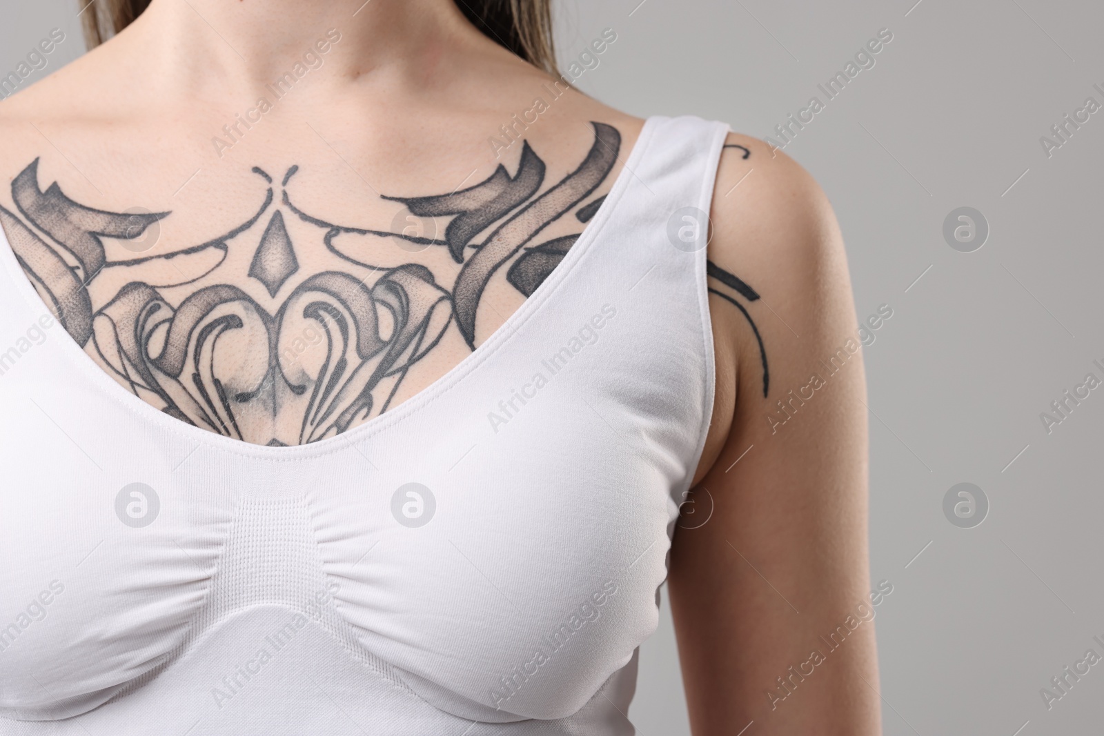Photo of Woman with cool tattoos on grey background, closeup