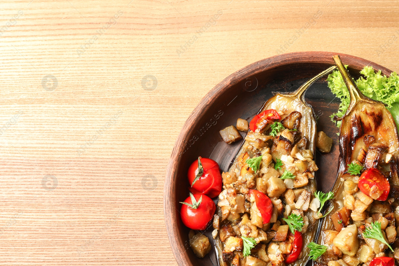 Photo of Bowl of tasty stuffed eggplants on wooden table, top view with space for text