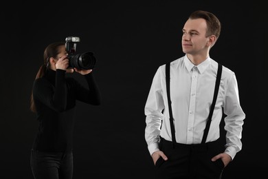 Professional photographer taking picture of man on black background