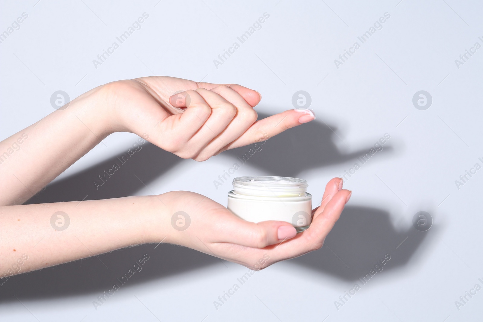 Photo of Woman with jar of cream on grey background, closeup