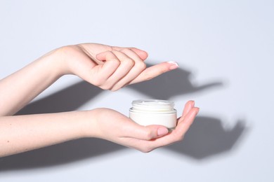 Photo of Woman with jar of cream on grey background, closeup