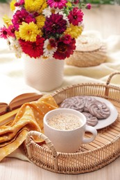 Photo of Cup of hot coffee, delicious cookies and beautiful bouquet on wooden table
