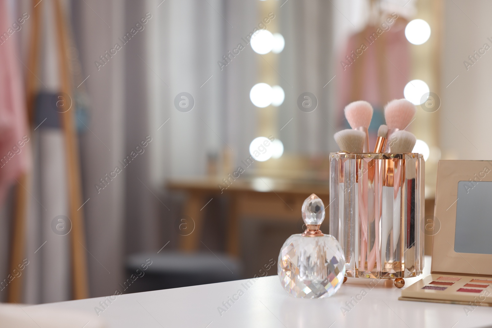 Photo of Set of brushes, eyeshadow palette and perfume on white table in makeup room, space for text