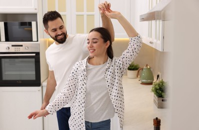 Photo of Happy lovely couple dancing together in kitchen