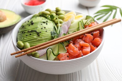 Photo of Delicious poke bowl with avocado, fish and edamame beans on white wooden table, closeup