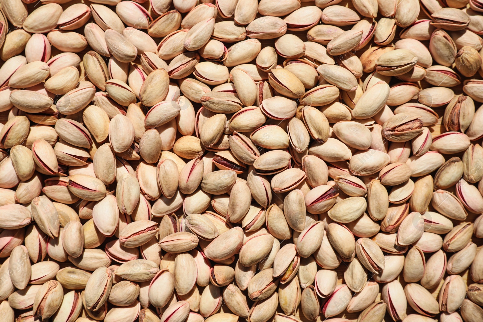 Photo of Many tasty pistachios as background, top view