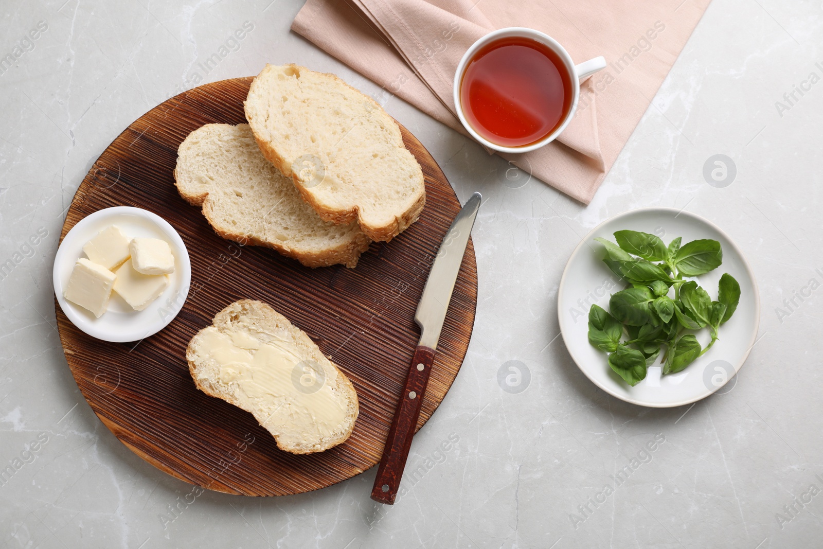 Photo of Flat lay composition with bread, butter and cup of tea on light background