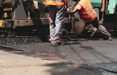 Photo of Workers laying new asphalt with paver, closeup. Road repair