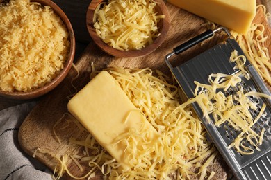 Grated, whole piece of cheese and grater on table, top view