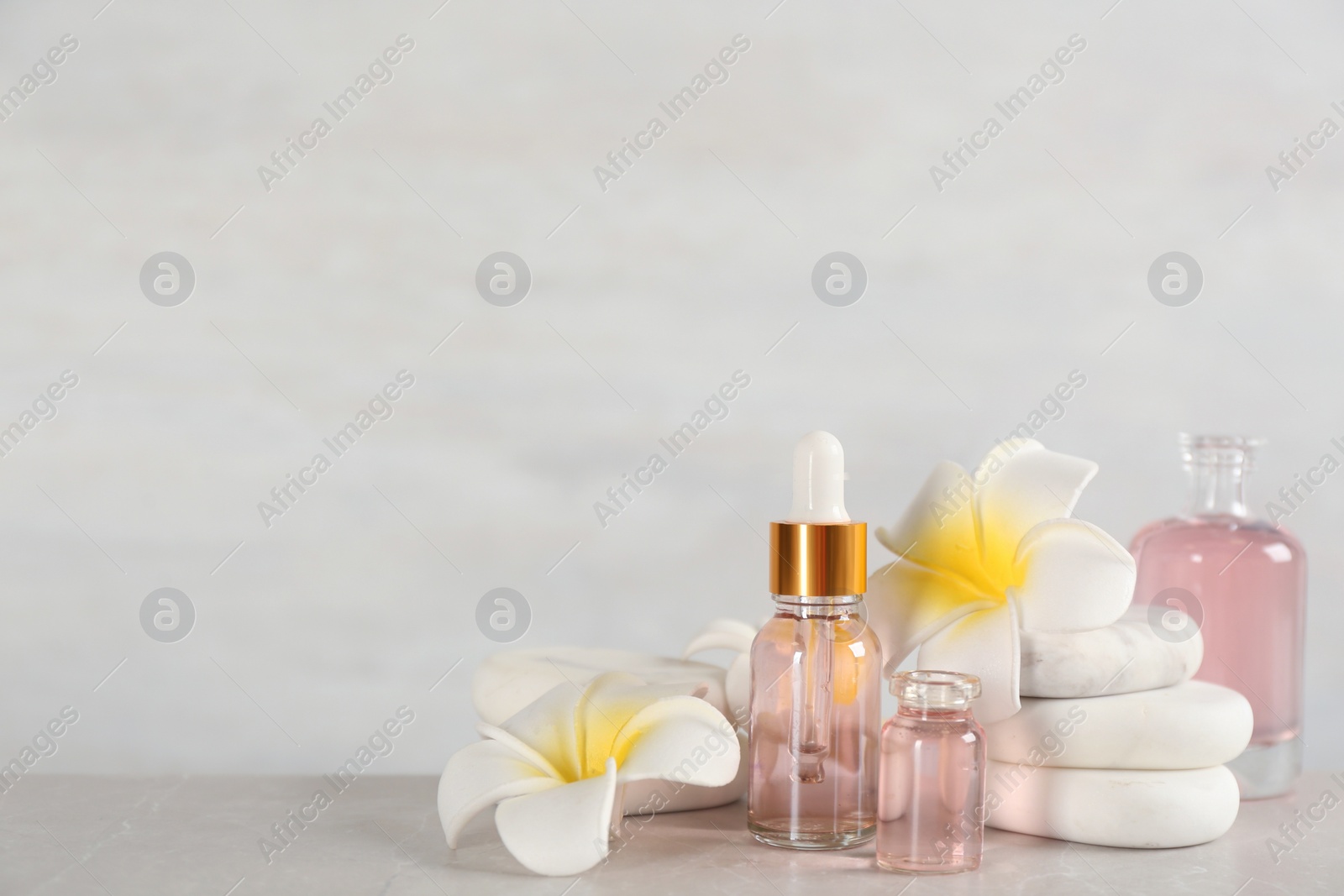 Photo of Beautiful composition with aroma oil and spa stones on marble table. Space for text