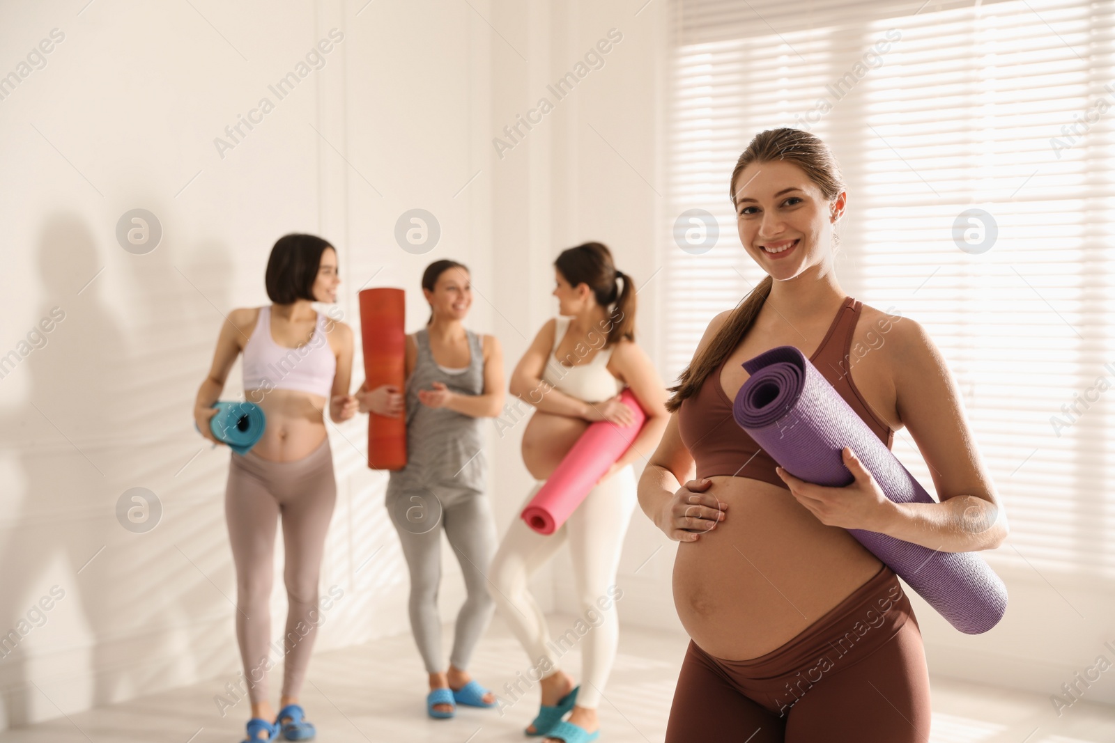 Photo of Group of pregnant women with mats in yoga class, space for text