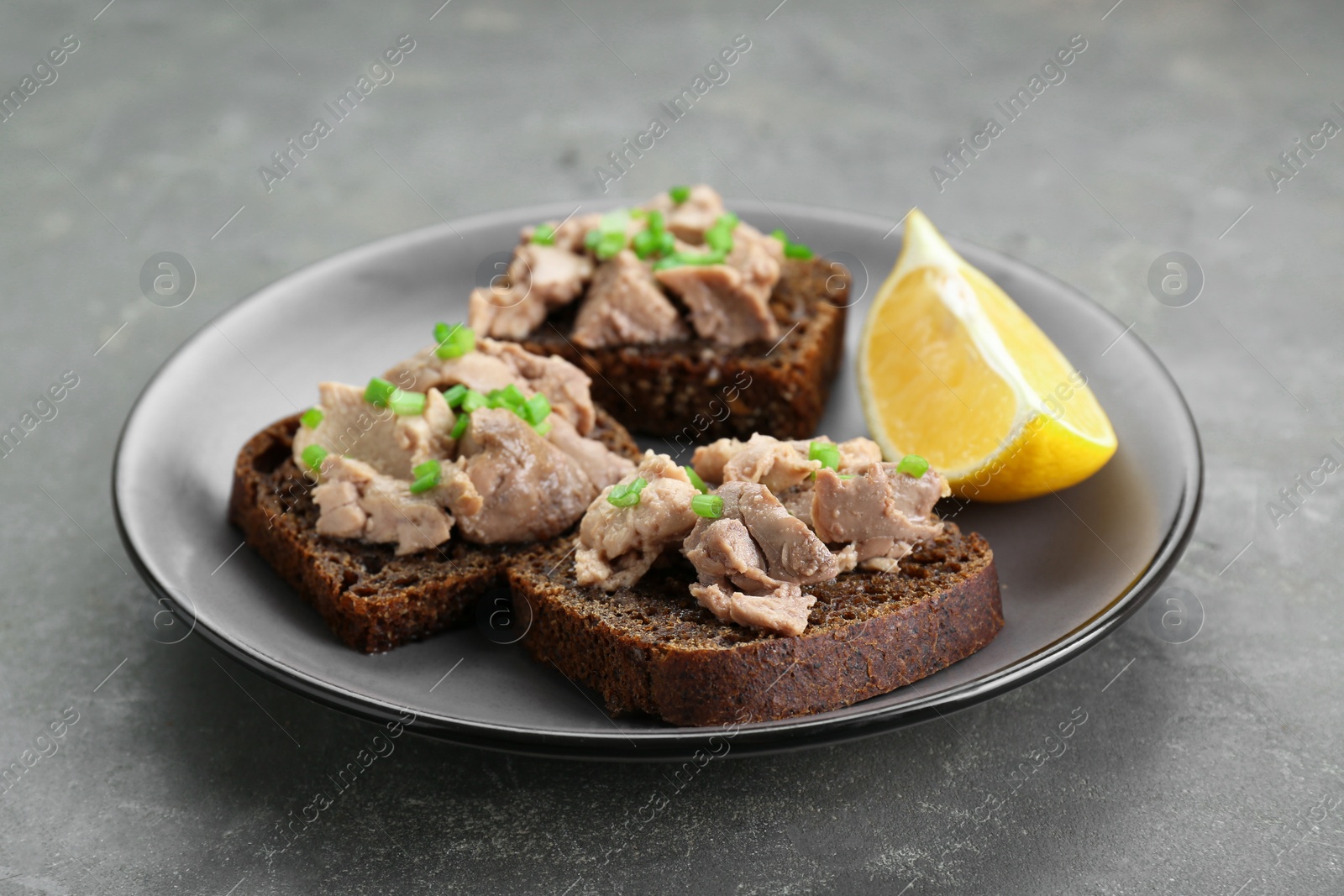 Photo of Tasty sandwiches with cod liver, lemon and green onion on light grey table