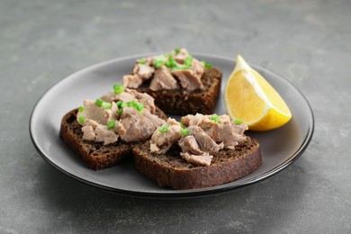 Photo of Tasty sandwiches with cod liver, lemon and green onion on light grey table