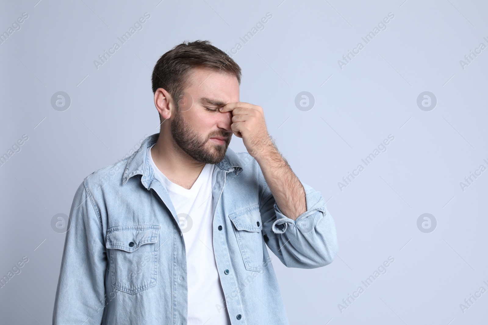 Photo of Young man suffering from headache on light background, space for text