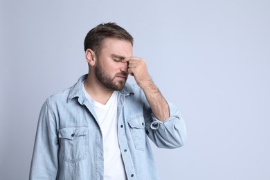 Photo of Young man suffering from headache on light background, space for text