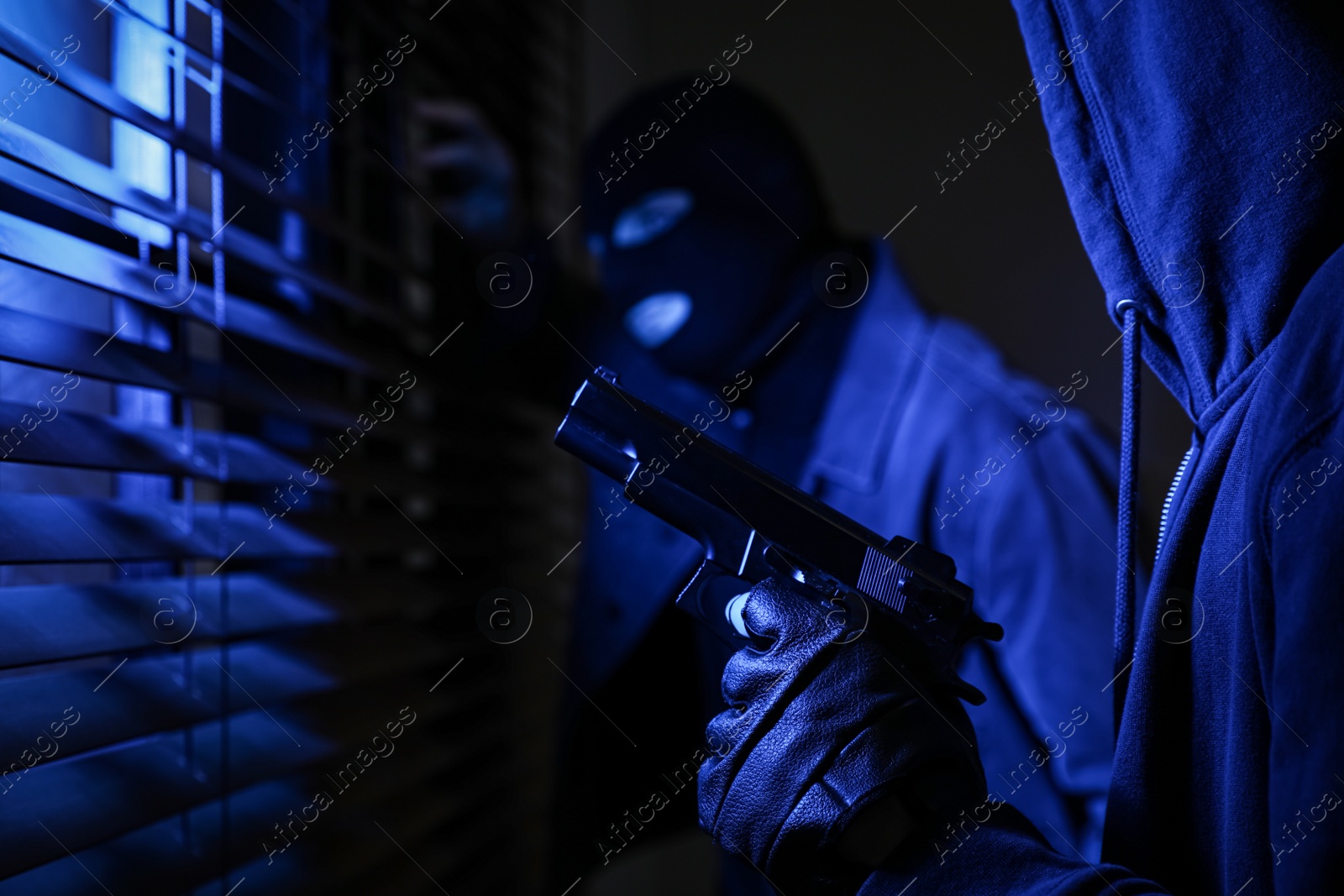 Photo of Dangerous criminals with gun near window indoors, closeup