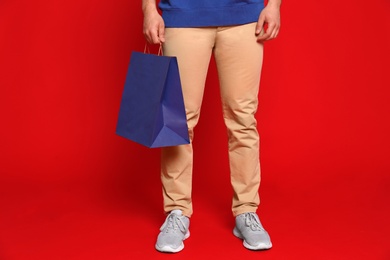 Young man with paper bag on red background, closeup