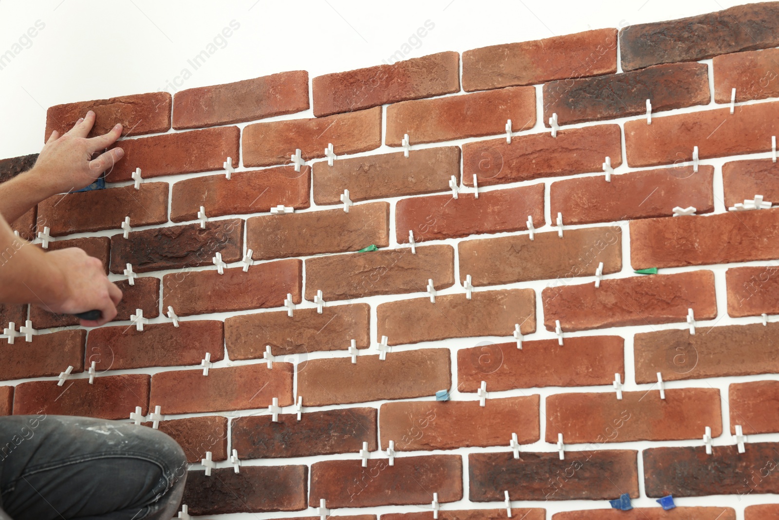 Photo of Professional builder gluing decorative brick on wall, closeup. Tiles installation process