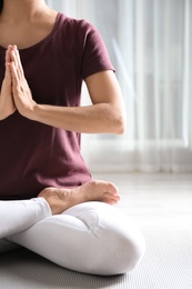 Photo of Woman practicing yoga on floor indoors, closeup