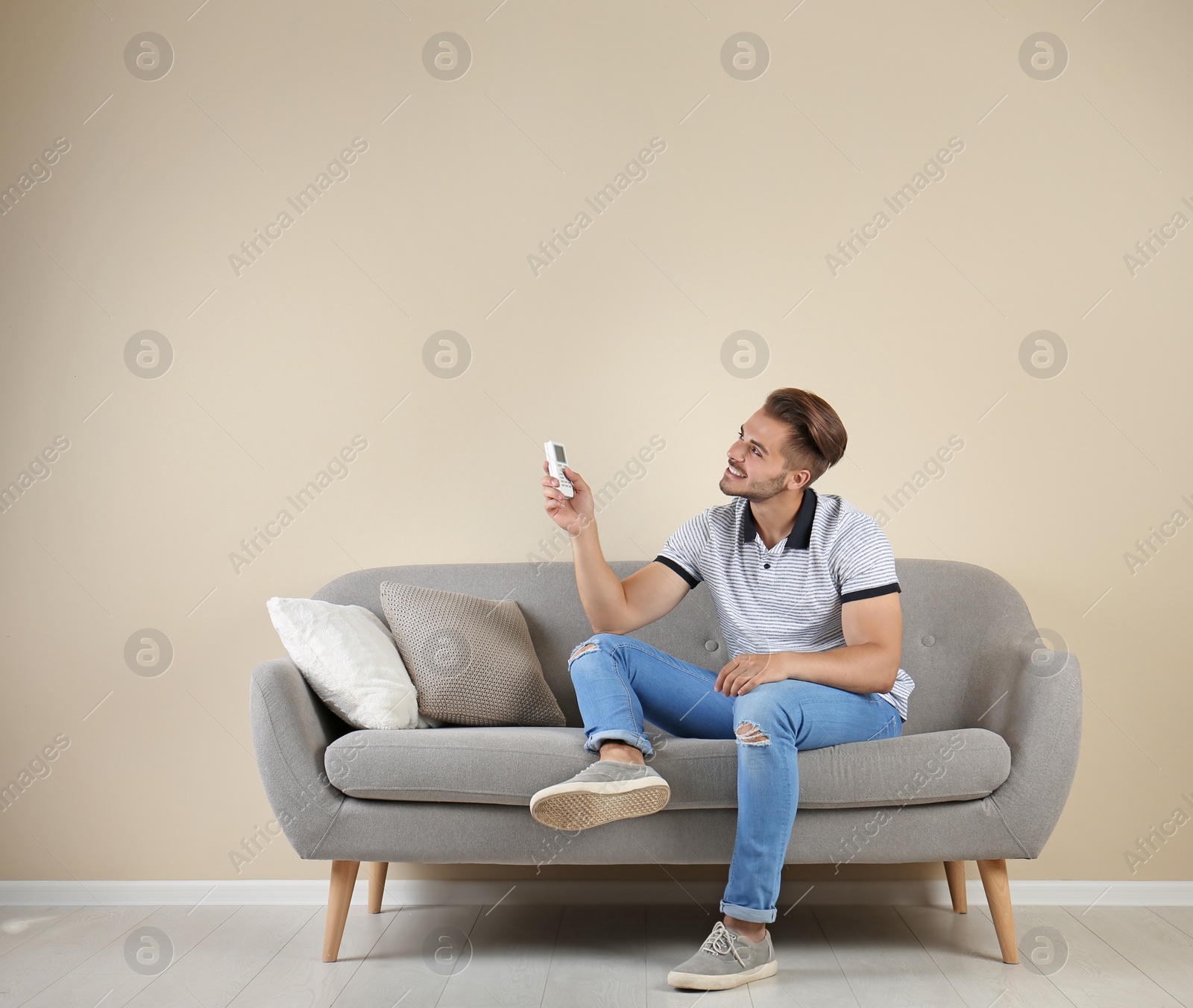 Photo of Young man with air conditioner remote at home