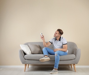 Young man with air conditioner remote at home