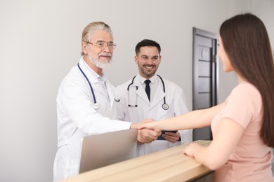 Photo of Happy senior doctor shaking hands with patient in clinic