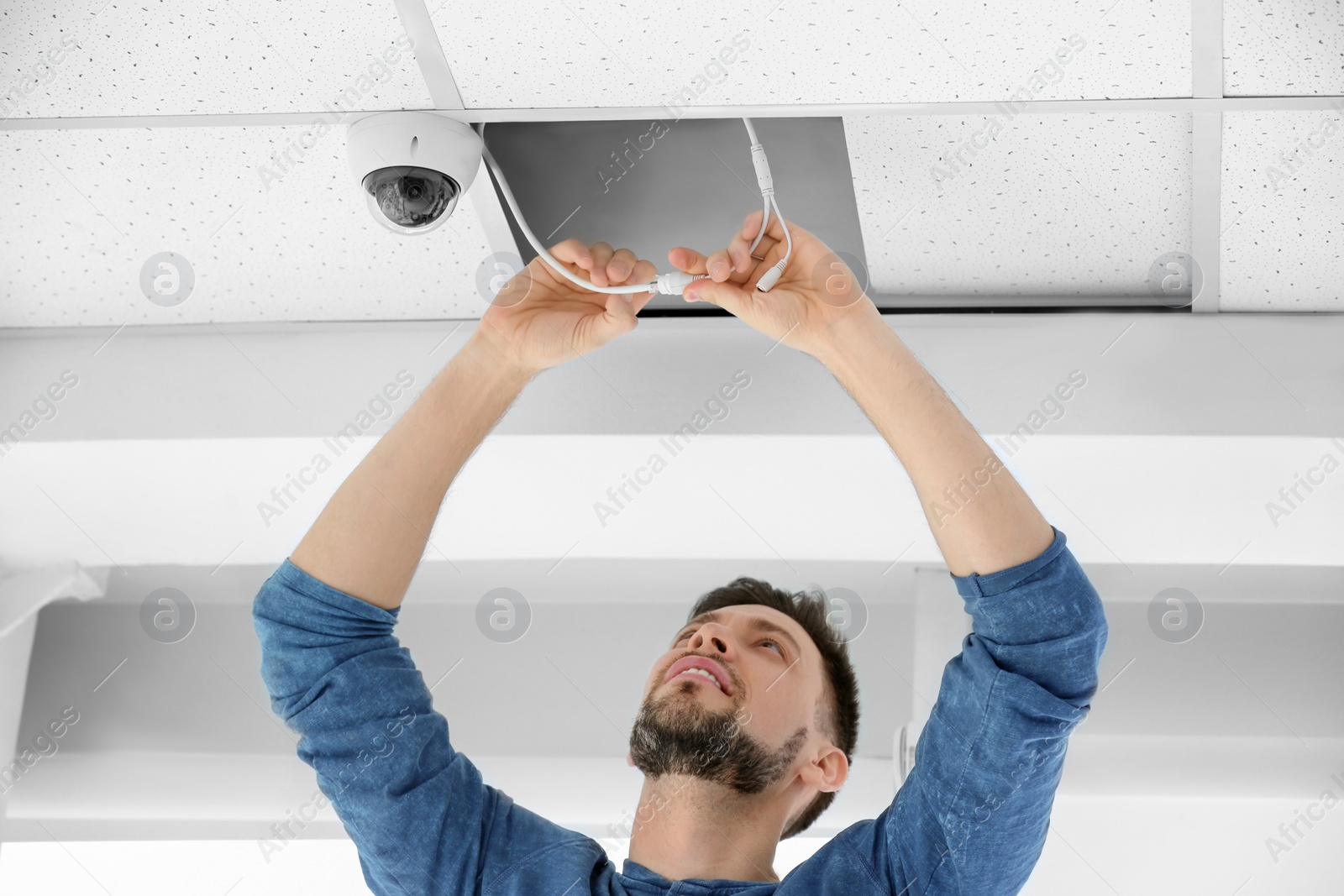 Photo of Technician installing CCTV camera on ceiling indoors