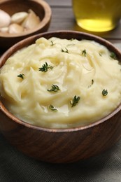 Photo of Bowl of delicious mashed potato with thyme on grey tablecloth, closeup