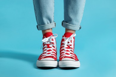 Photo of Woman in stylish gumshoes on light blue background, closeup