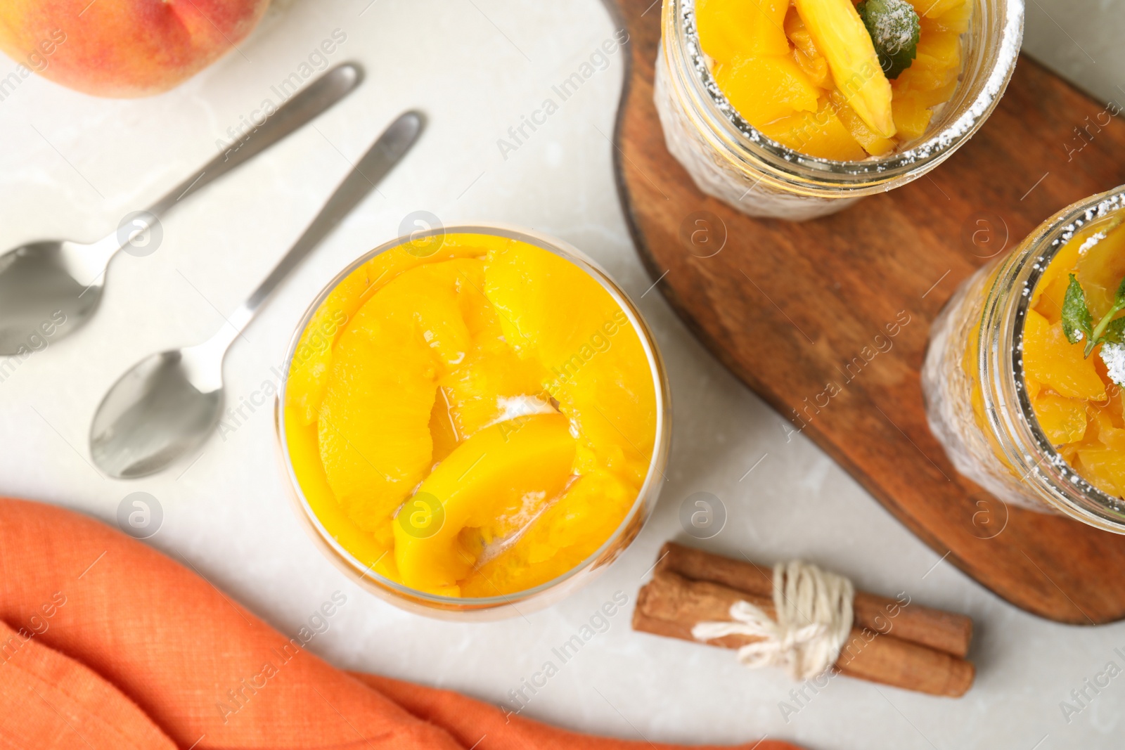 Photo of Tasty peach dessert with yogurt served on light table, flat lay